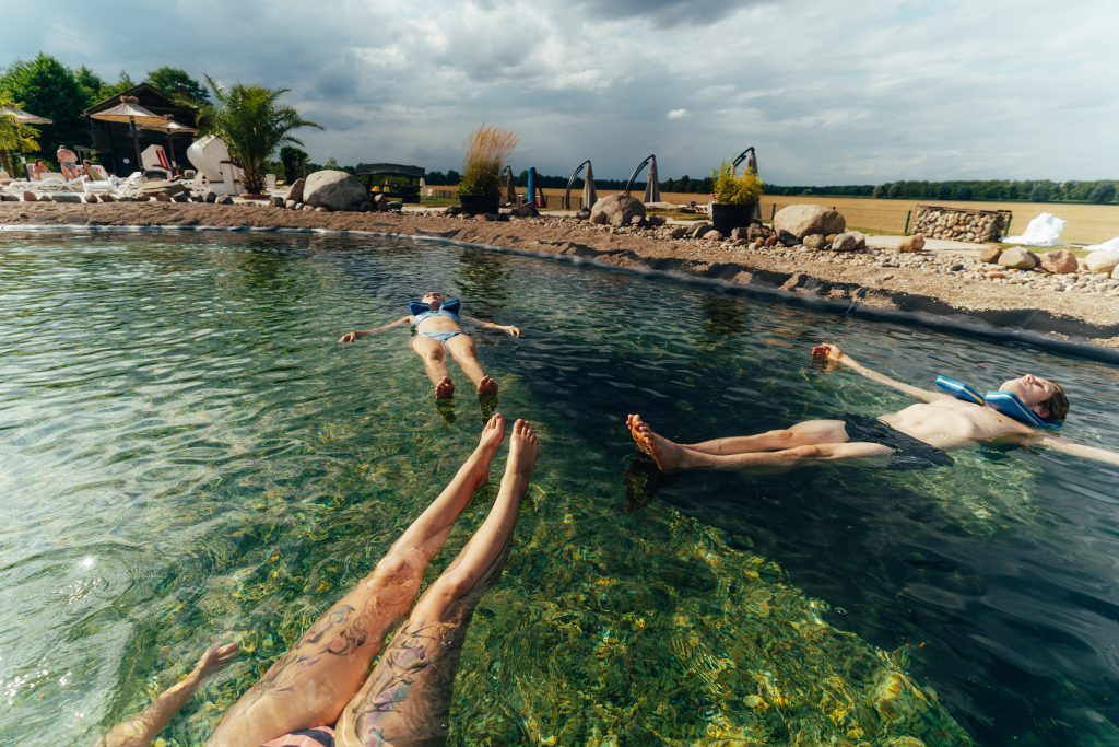 Drei Personen entspannen und treiben auf dem Rücken im Außenpool der Kristall Therme Bad Wilsnack.