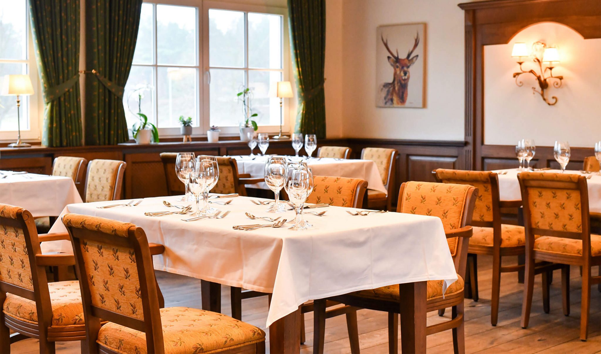Restaurant mit gedeckten Tischen und Holzstühlen.
